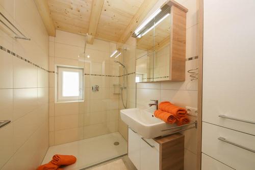La salle de bains blanche est pourvue d'un lavabo et d'une douche. dans l'établissement Spitzbua, à Saalfelden