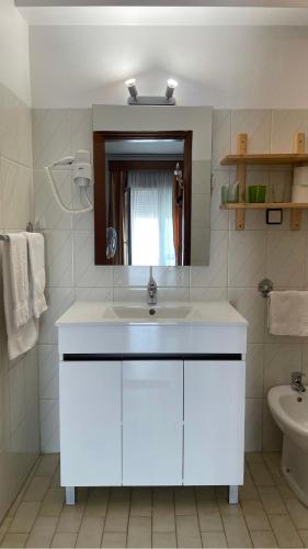 a white bathroom with a sink and a mirror at Pensao Vista Bela in Miranda do Douro