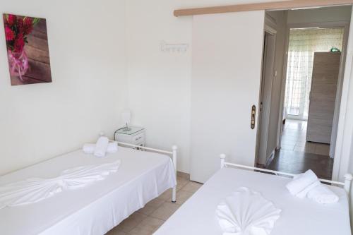 a white bedroom with two beds and a hallway at Apartment in Asprovalta in Asprovalta