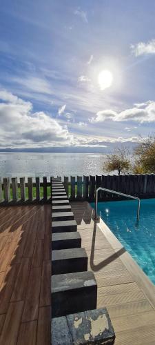 a swimming pool with stairs next to the water at Departamento Pucón - Salida directa al Lago Villarrica in Pucón