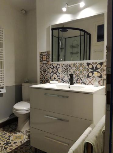 a bathroom with a sink and a toilet and a mirror at Gîte les 4 Vents in Pradelles
