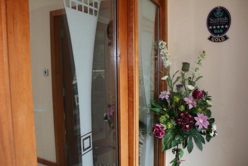 a glass door with a vase of flowers on it at Ayrs and Graces - Luxury Bed and Breakfast in Ayr