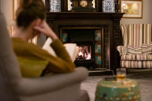 a woman sitting in front of a fire in a fireplace at Emmet Hotel in Clonakilty