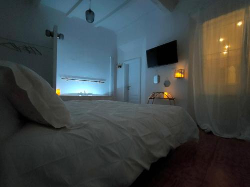 a bedroom with a white bed and a television at Il Sitarein in Bologna