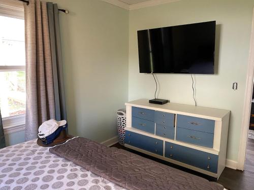 een slaapkamer met een bed en een dressoir met een flatscreen-tv bij Country Comfy Right in Town in Charleston