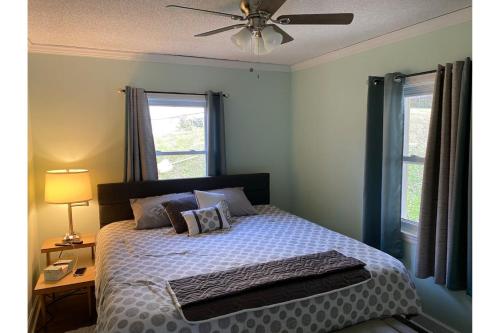 a bedroom with a bed with a ceiling fan and two windows at Country Comfy Right in Town in Charleston