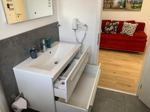 a bathroom with a white sink and a red couch at ARGENTA Living 42 in Künzell