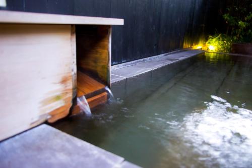 a pool of water next to a wooden fence at かわもと別邸９２６ in Yufuin