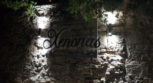 a sign on the side of a stone wall with lights at Xenonas in Kamilari