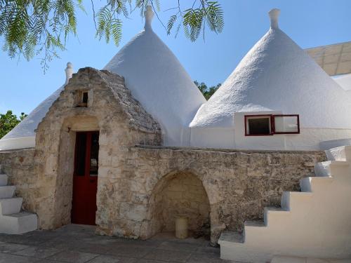 ein weißes Gebäude mit einer roten Tür und einer Treppe in der Unterkunft Trullo Tojo in Ostuni