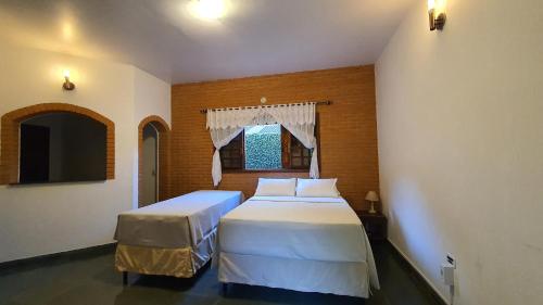 1 dormitorio con 2 camas y ventana en Pousada Santo Antonio, en Santo Antônio do Pinhal