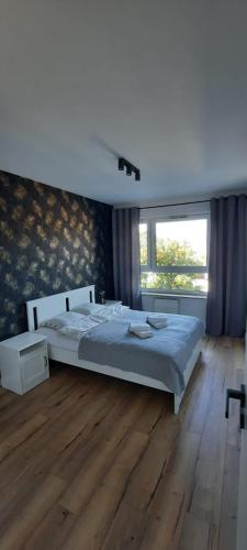 ein Schlafzimmer mit einem großen Bett und Holzboden in der Unterkunft Apartament Nel in Zielona Góra