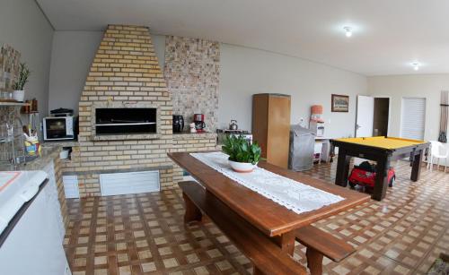 a living room with a table and a brick fireplace at Casas do Preto in Guarda do Embaú