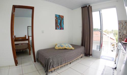 a bedroom with a bed and a large window at Casas do Preto in Guarda do Embaú