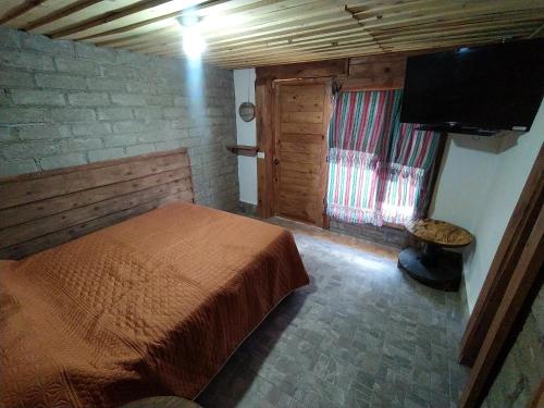 um quarto com uma cama e uma televisão de ecrã plano em Habitaciónes estilo cabaña las Herraduras em Creel