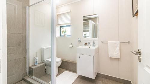 a white bathroom with a toilet and a sink at East Point in Durban