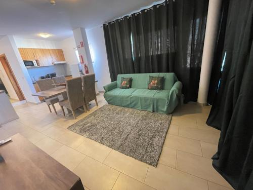 a living room with a green couch and a table at Esmeralda Holidays Apartments in Funchal