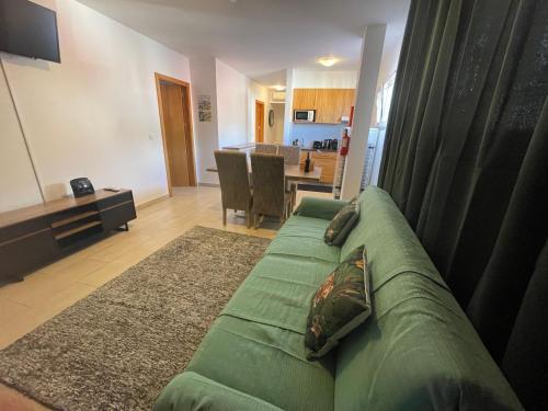 a living room with a green couch and a kitchen at Esmeralda Holidays Apartments in Funchal