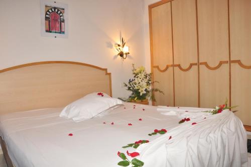 a white bed with red rose petals on it at Hotel Nesrine Hammamet in Hammamet