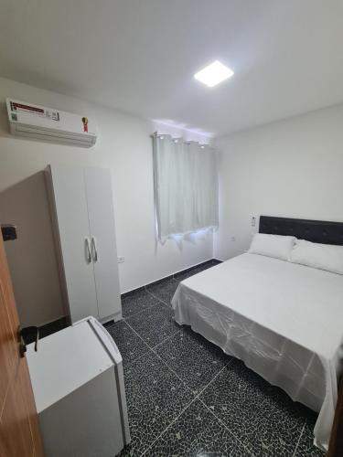 ein Schlafzimmer mit einem weißen Bett und einem Fenster in der Unterkunft Suites jangadeiro Maragogi 3 RUA JANGADEIROS 215 in Maragogi