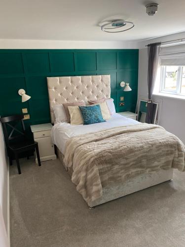 um quarto com uma cama grande e uma parede verde em Stratford House em Stratford-upon-Avon