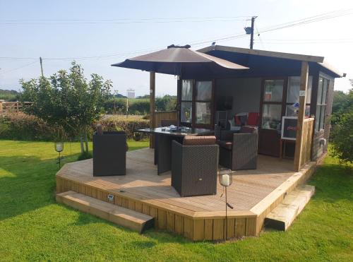 a house with a deck with an umbrella at Broadlea of Robgill Country Cottage Accommodation in Ecclefechan
