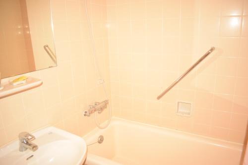 a bathroom with a tub and a sink and a toilet at Kagetsuen in Hakone