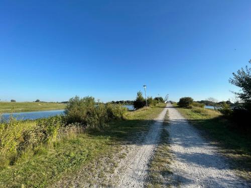 a dirt road next to a river at Wangerbrise in Wangerland