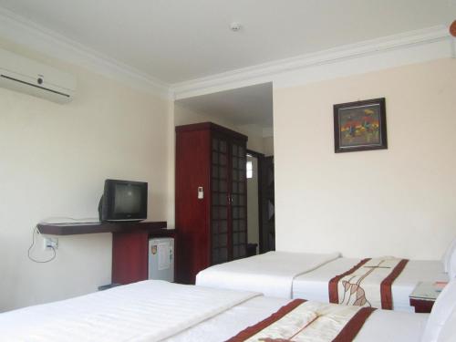 a room with two beds and a tv on the wall at Nhiet Doi Hotel in Tuy Hoa