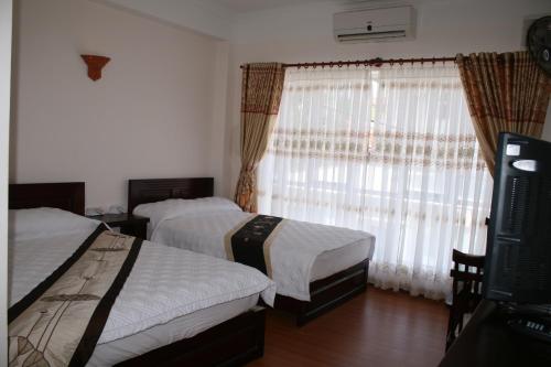 a hotel room with two beds and a window at Nhiet Doi Hotel in Tuy Hoa