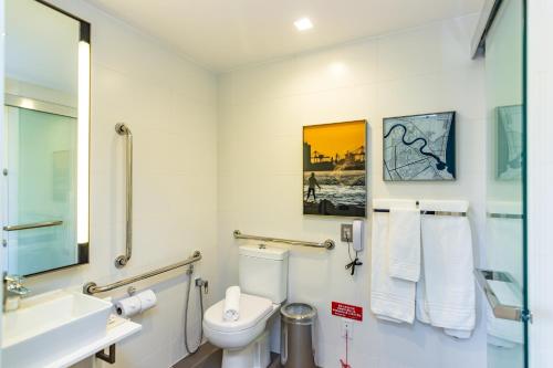 a bathroom with a toilet and a sink and a mirror at Mercure Itajai Navegantes in Itajaí