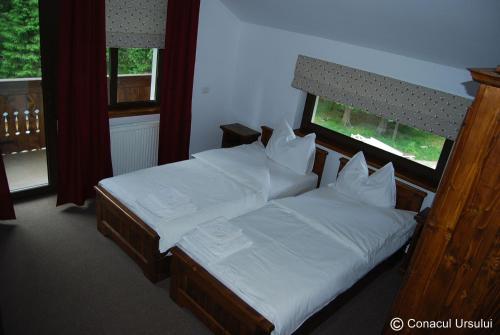 a bedroom with two beds with white sheets and a window at Conacul Ursului in Cumpăna