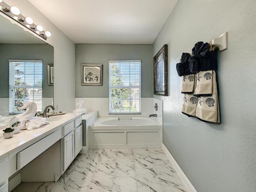 a bathroom with a tub and a sink and a mirror at Luxury Family Villa Pool Hot Tub Close to Disney in Orlando