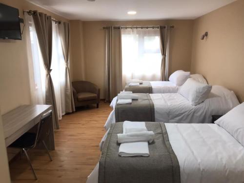 a hotel room with three beds with towels on them at Gran Hotel Aysen in Puerto Aisén