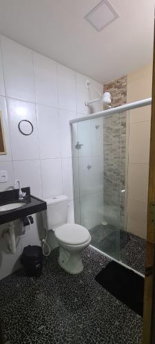 a bathroom with a toilet and a glass shower at Suites jangadeiro Maragogi 3 RUA JANGADEIROS 215 in Maragogi