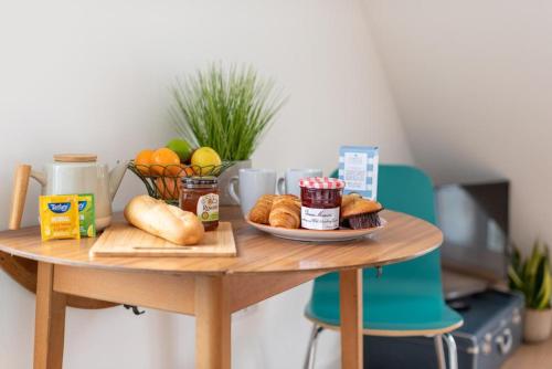 a table with a plate of bread and a plate of fruit at Bells Chapel - Bright Rooftop Apartment in the Centre of Town with Juliet Balconies in Falmouth