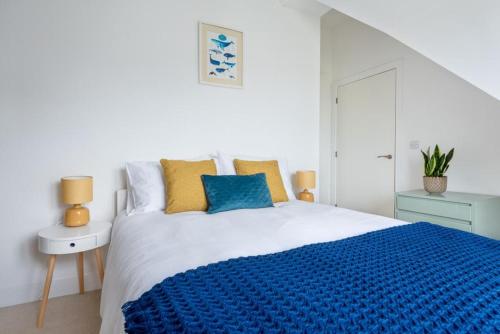 a white bedroom with a blue blanket on a bed at Bells Chapel - Bright Rooftop Apartment in the Centre of Town with Juliet Balconies in Falmouth