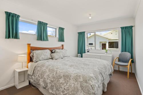 a bedroom with a large bed and green curtains at Karori Kabin - Karori Holiday Home in Wellington