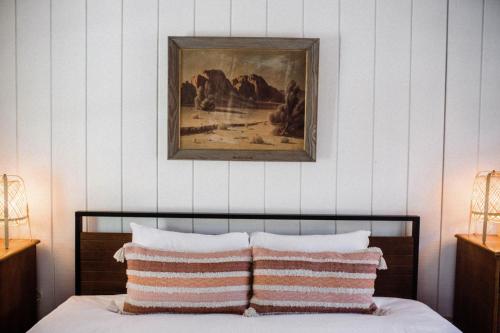 a bedroom with a painting above a bed with two pillows at The Good House- Hot Spring Hideaway in Desert Hot Springs