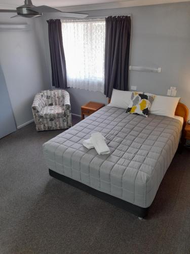 a bedroom with a large bed and a chair at Civic Motel Grafton in Grafton