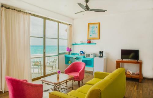 a living room with a yellow couch and pink chairs at Villa Elena Isla Mujeres in Isla Mujeres