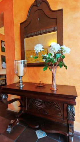 a table with a vase of flowers and a mirror at Hotel Boutique Casa Montalvo Cuenca in Cuenca