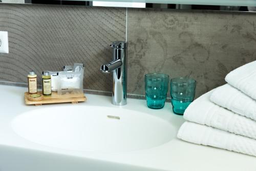 a bathroom sink with towels and a faucet and glasses at Hotel Terrace in Bettendorf