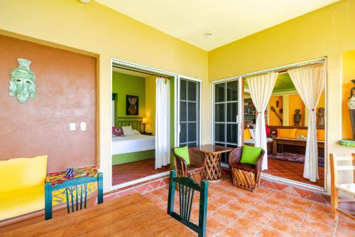 a living room with yellow walls and a table and chairs at Villas Jardin Del Mar in Cruz de Huanacaxtle
