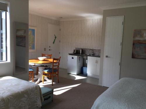 
a room with a bed, table and a refrigerator at Abel Tasman Sands BnB in Marahau
