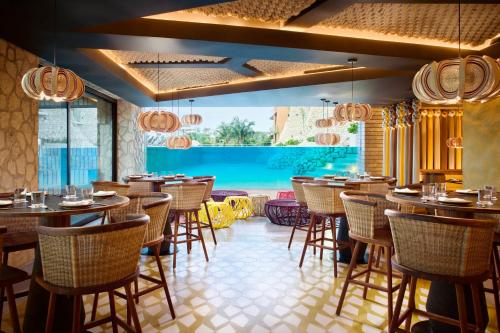 a restaurant with tables and chairs and a pool at Hotel Xcaret Arte - All Parks All Fun Inclusive - Adults Only in Playa del Carmen