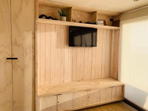 a room with a tv and a wooden wall at PUPUYA LODGE cabaña A, Matanzas in Matanzas