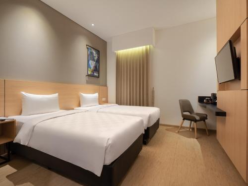 una camera d'albergo con due letti e una televisione di Hotel 88 Blok M Jakarta By WH a Giacarta