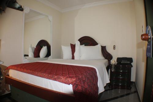 1 dormitorio con 1 cama grande con manta roja y blanca en Lafont Park Hotel, en Bogotá