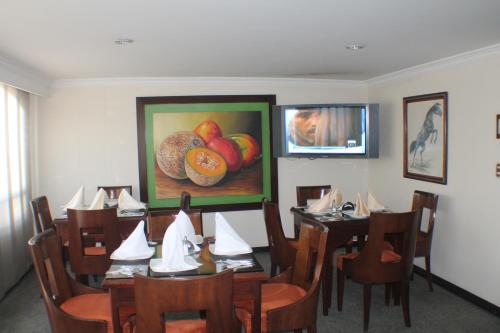 un comedor con mesa y sillas y una pintura de fruta en Lafont Park Hotel, en Bogotá